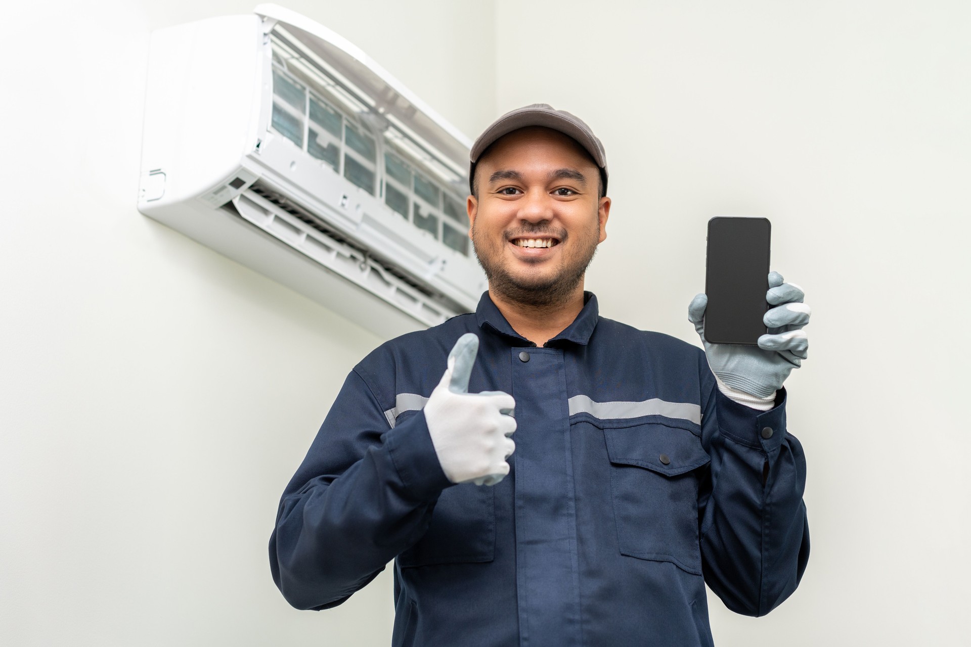 Air conditioner call service by cell phone. Air conditioner cleaning technician He opened the front cover and took out the filters and washed it. Holding smartphone