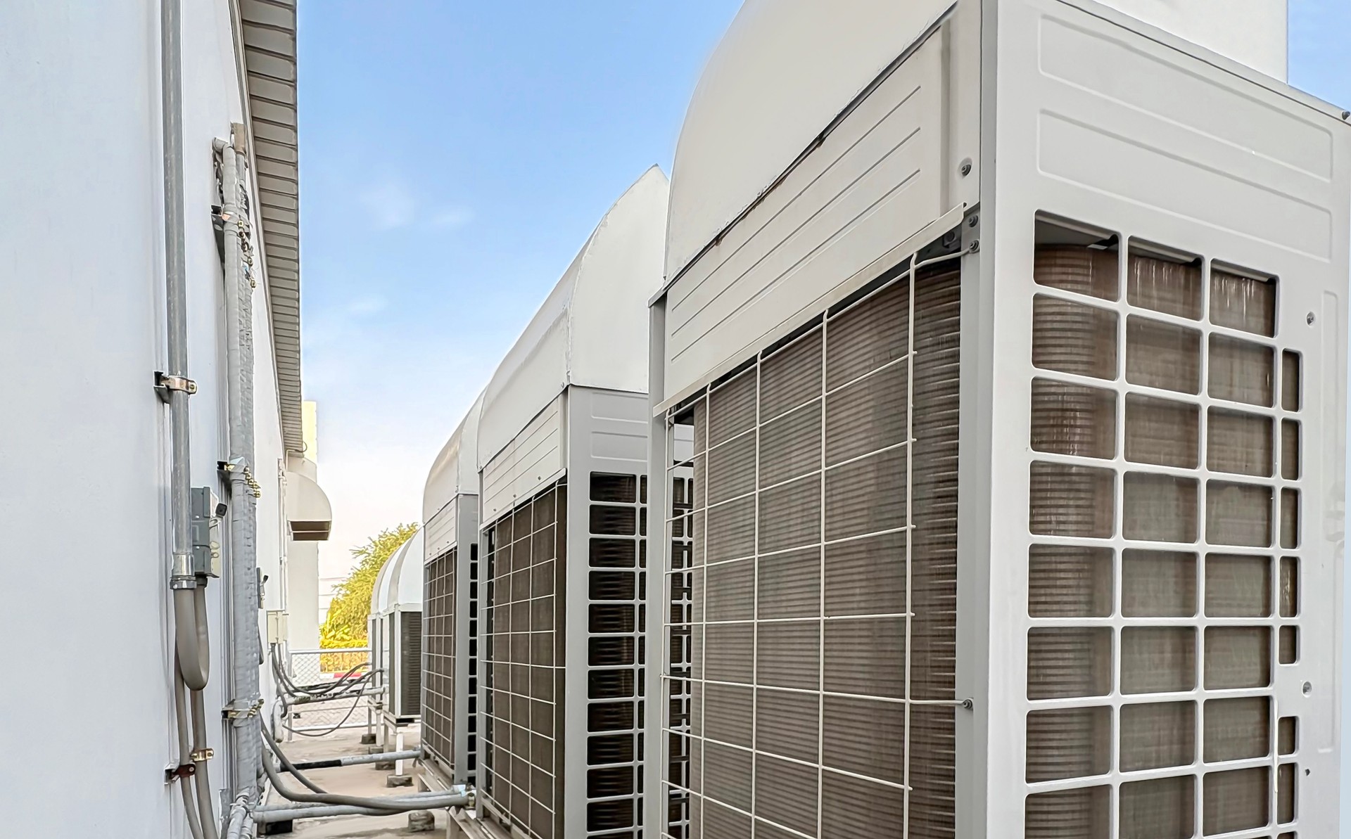 Air conditioning (HVAC) on the roof of an industrial building with blue sky and clouds.